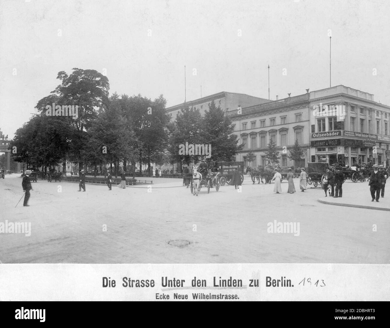 'In the picture a coal truck of the company Efrem & Bicknase is driving on the street Unter den Linden, corner Wilhelmstrasse, through Berlin. On the right are the stores of Schultheissen Reinhold Jacksch, the tobacconist Loeser & Wolff and above them the information center and brochure edition of the Verband deutscher Ostseebaeder (''Association of German Baltic Sea Resorts''). On the left in the background is the Brandenburg Gate. The picture was taken in 1913.' Stock Photo