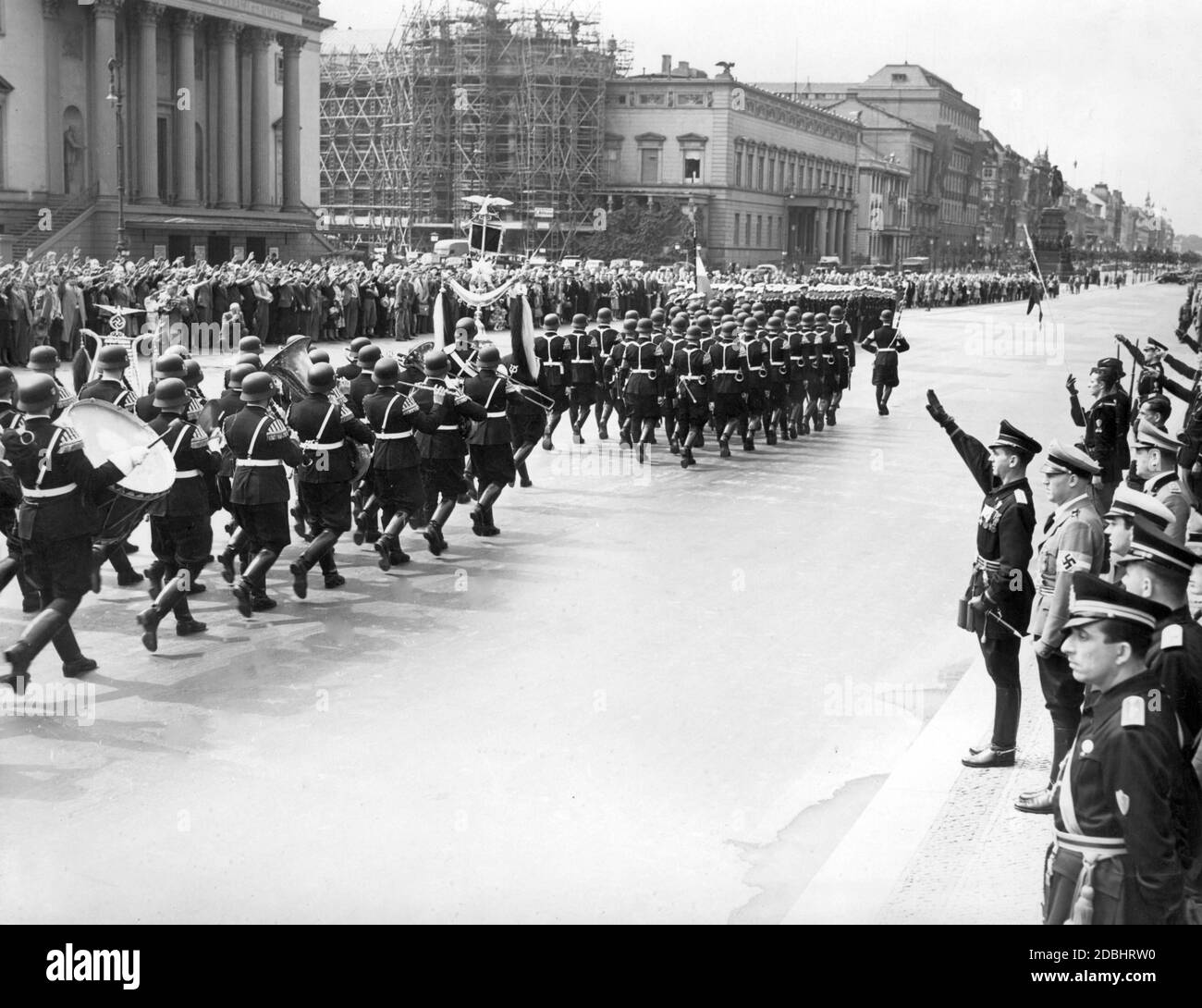The honor guard of the Leibstandarte SS Adolf Hitler marches past the leader of the Italian Young Fascists (Gioventu Italiana del Littorio) Federale Sandro Bonamici (at the same time Gauleiter of Verona, right in the picture, performing the Nazi salute) and Chief of Staff Hartmann Lauterbacher (half right behind him). The occasion was a wreath-laying ceremony at the memorial (Neue Wache) in Berlin Unter den Linden on August 19, 1939 by the participants of the long-distance bicycle tour Rome-Berlin-Rome. In the background (from left to right) the State Opera, the Old Library (in  scaffolding), Stock Photo