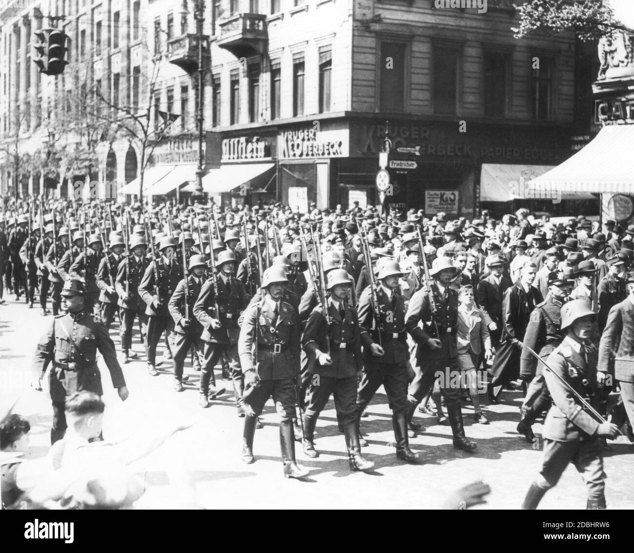 'The photograph from April 1935 shows the deployment of a guard unit of the new German Luftwaffe at the street corner Unter den Linden, Friedrichstrasse in Berlin. Accompanied by the spectators, the Luftwaffe soldiers walk to the changing of the guard. It was not until March 1935 that general conscription was reintroduced in the National Socialist Germany. The cigar store ''Krueger und Oberbeck'' is located on the street corner.' Stock Photo