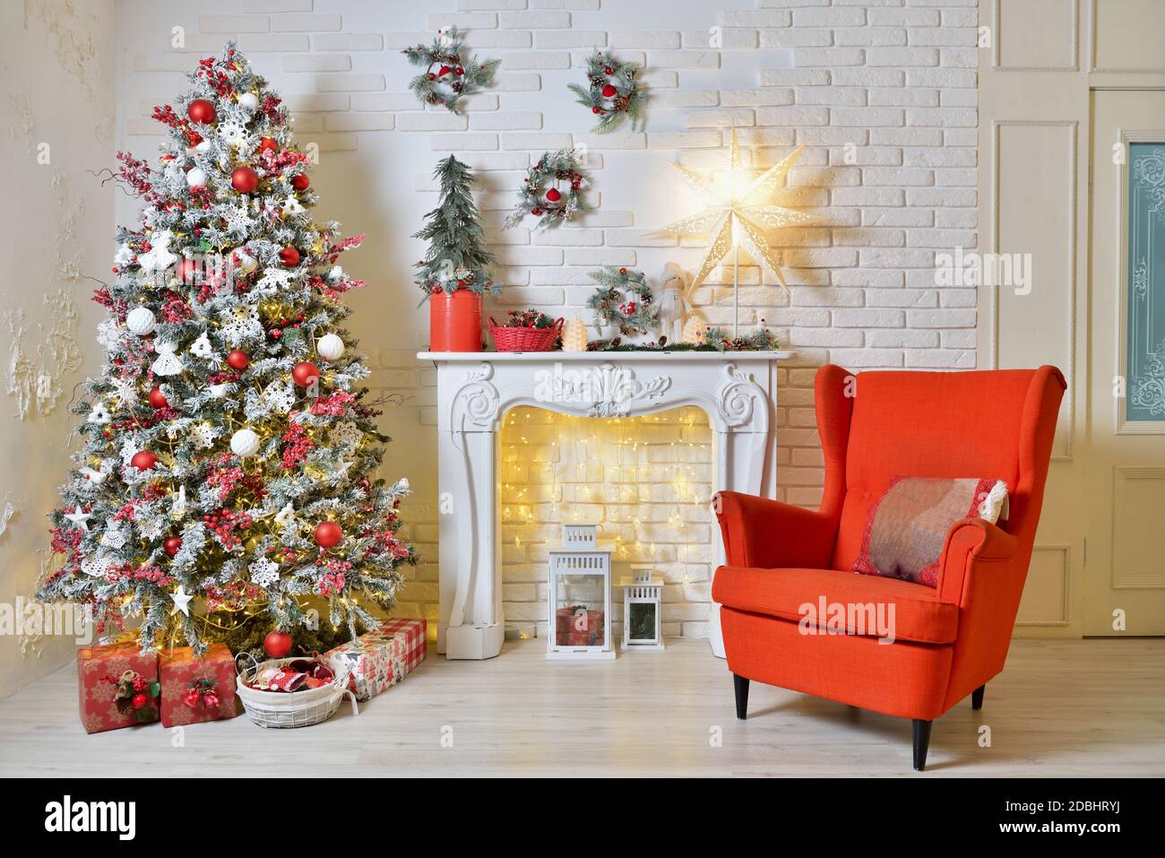Cozy Christmas decorations in living room with red armchair, Christmas tree and garlands Stock Photo