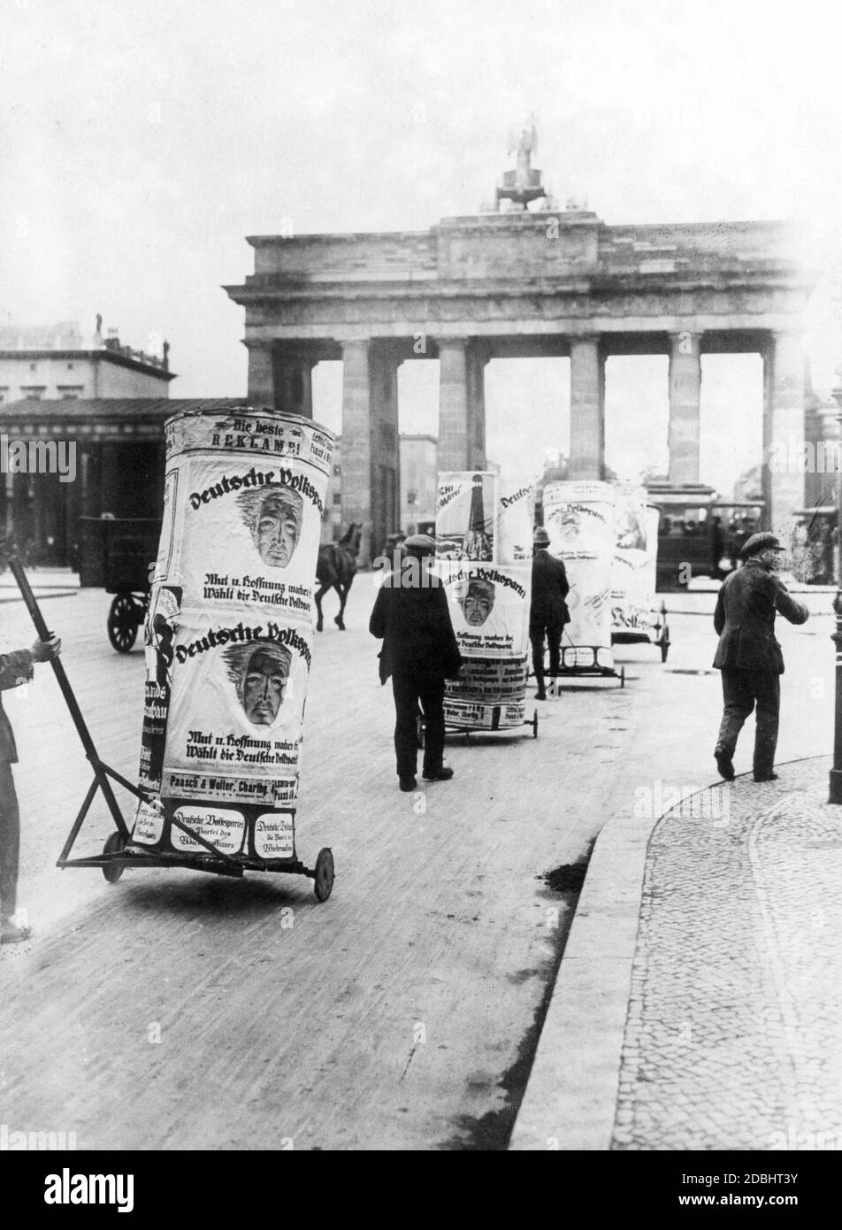 'Before the Reichstag elections on June 6, 1920, several men push advertising pillars with election posters of the German People's Party (DVP) in front of the Brandenburg Gate through Berlin. The party campaigns for voter support with slogans such as ''Courage and Hope Make People Free, Vote for the German People's Party'' and ''German People's Party / the Party of / Reconstruction''.' Stock Photo