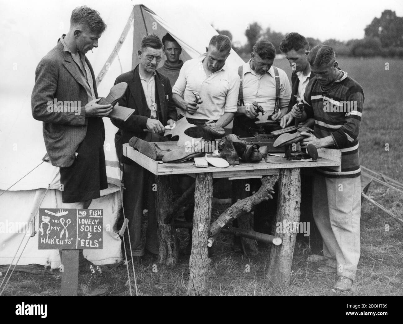 A group of Welsh unemployed people manufacture shoes in a mobile workshop that is part of a course program organized by bachelor students for the unemployed in Oxford. M.G. MacCooper (left), captain of the rugby team, looks at the goods. Stock Photo