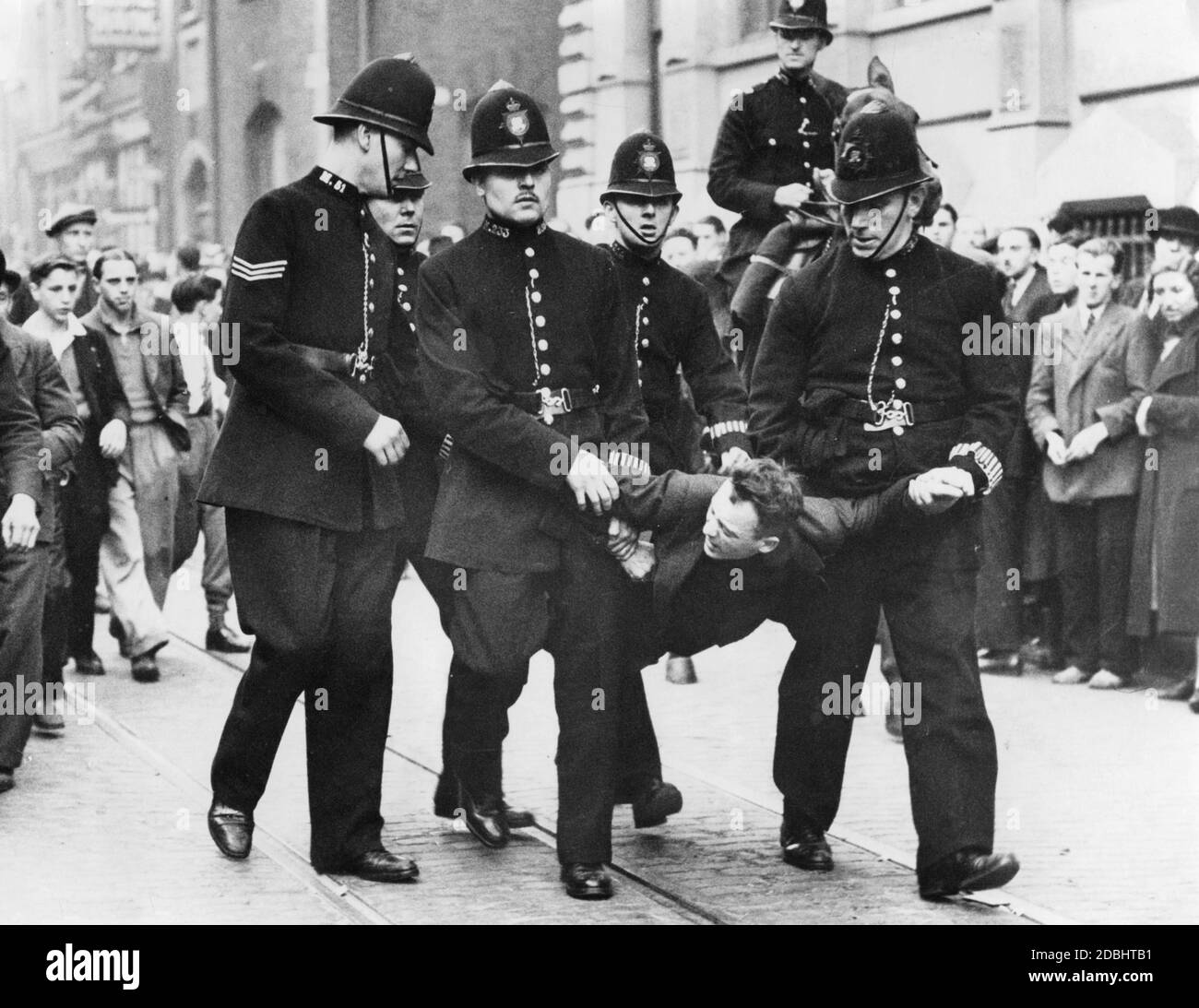 'Police officers carry away an arrested demonstrator. On the occasion of a march of the ''British Union of Fascists'' (BUF) numerous anti-fascist demonstrators had gathered in London and protested against the march.' Stock Photo