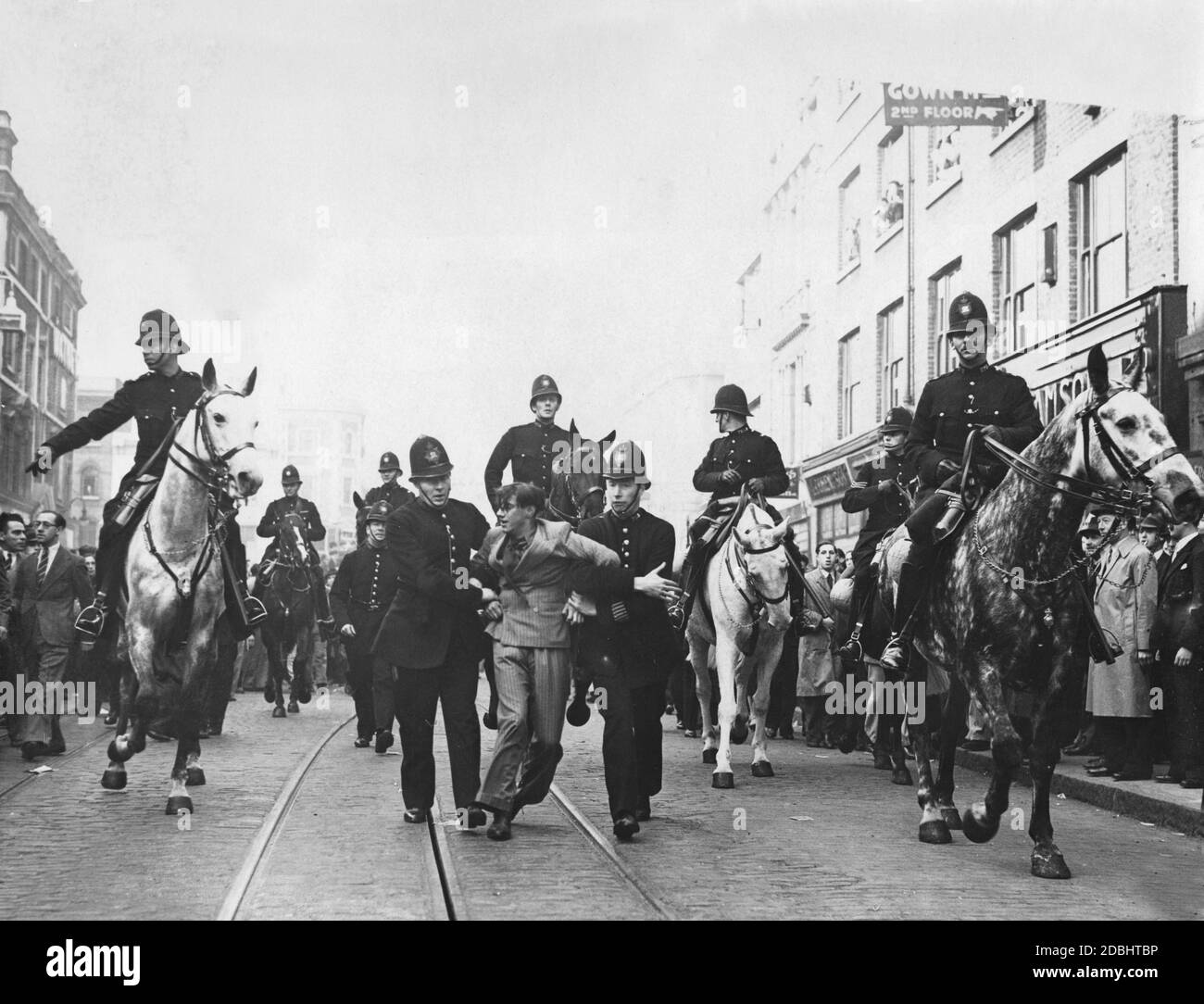 'Police officers are taking an arrested demonstrator away. On the occasion of a march of the ''British Union of Fascists'' (BUF), numerous anti-fascist demonstrators had gathered in London and protested against the march.' Stock Photo