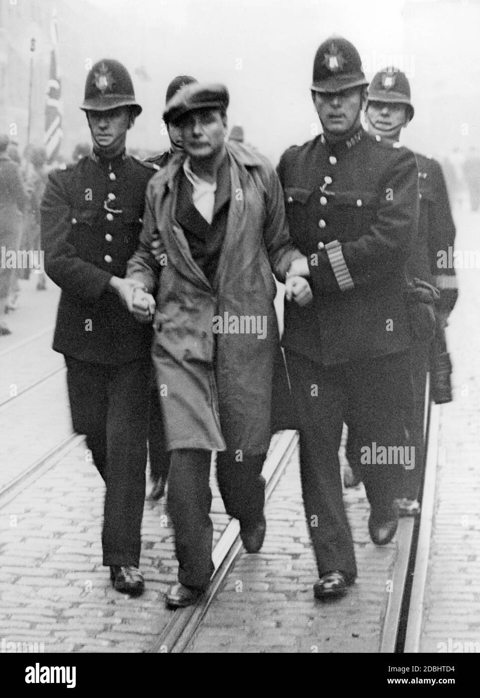 'Policemen take an arrested demonstrator away in Bermondsey. In the course of a march of the ''British Union of Fascists'' (BUF) on the occasion of its five-year existence there were numerous clashes between anti-fascist demonstrators and the police.' Stock Photo