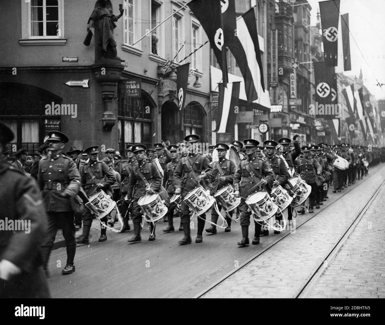 View of a British contingent of the International Force for the Protection of the Saar Referendum in a street decorated with swastika flags and imperial flags in Saarbruecken. Stock Photo
