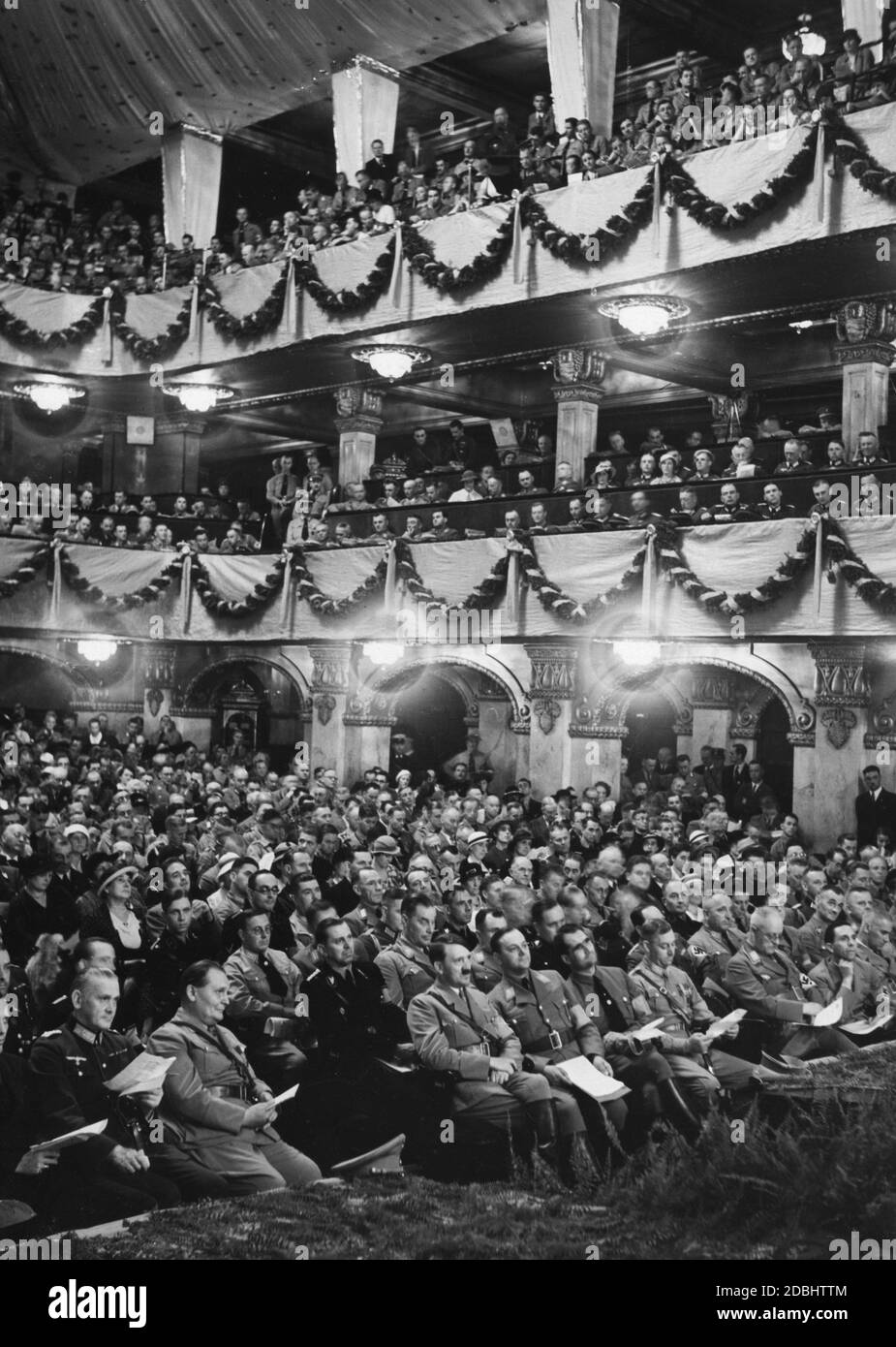 View of the first row of spectators at the cultural conference of the NSDAP in Nuremberg's Apollo Theater, where Alfred Rosenberg and Adolf Hitler give speeches and the Reich Symphony Orchestra offers a musical performance. 1st row from left: Johann Ludwig Graf Schwerin von Krosigk, Colonel General Werner von Blomberg, Hermann Goering, Adolf Hitler, Alfred Rosenberg, Rudolf Hess, Viktor Lutze, ?, Joseph Gobbels, Wilhelm Frick (behind him Max Amann). In the 2nd row behind von Blomberg, Erich Raeder. Behind Adolf Hitler: Julius Schaub, on the right Wilhelm Brueckner, Martin Bormann, ? and Stock Photo