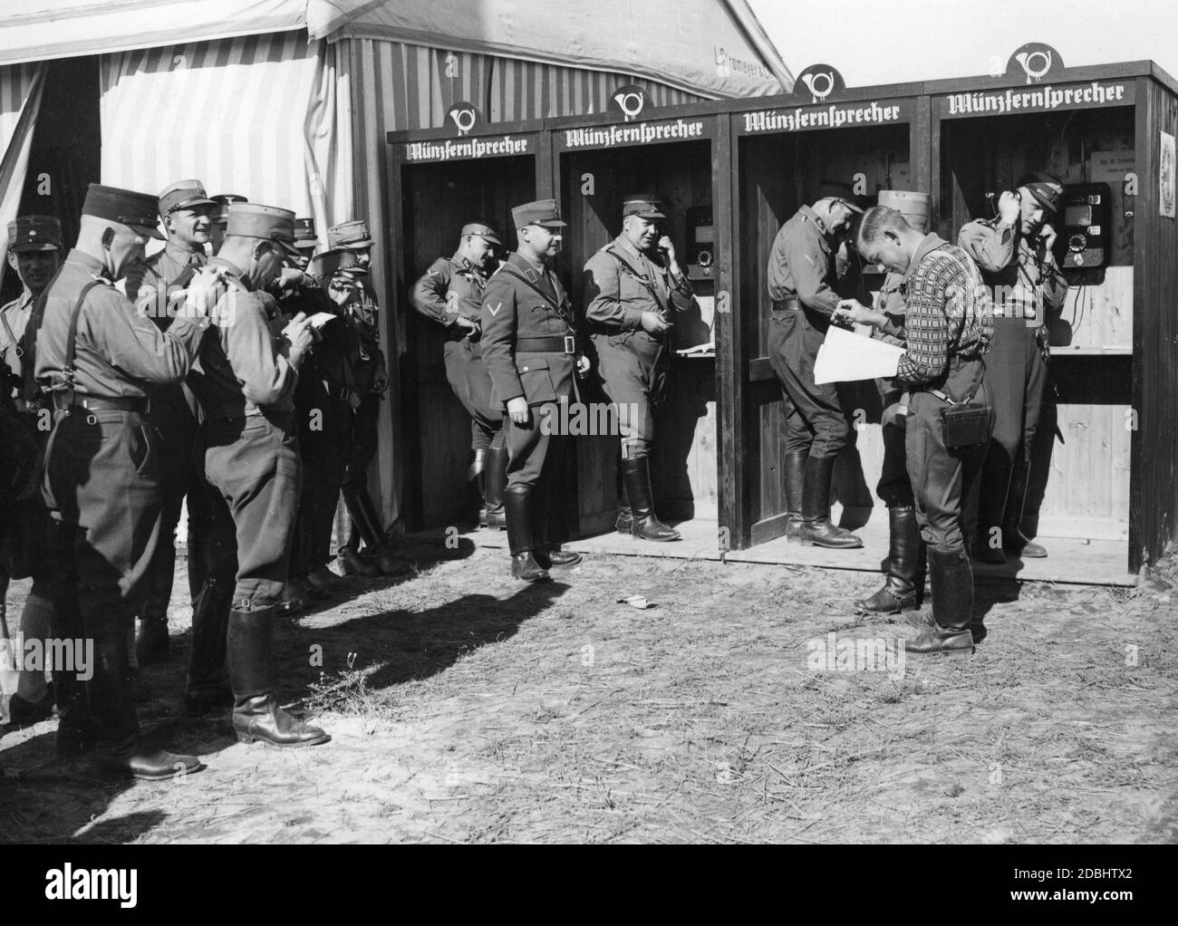 In the Nuremberg-Langwasser tent camp, the people in the camp line up in front of four pay phones at the camp post office. Stock Photo