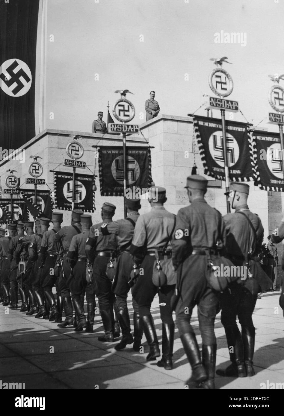 Adolf Hitler and, to his left, Viktor Lutze take the salute of the marching SA standard bearers from the rostrum of the Luitpold Arena on the Nuremberg Nazi Party Rally Grounds. Stock Photo