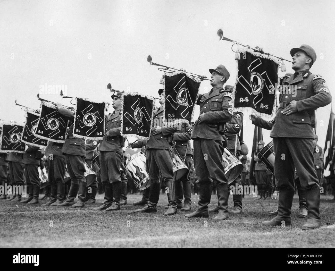 Herald trumpets of the Labor Service sound the roll call of the FAD on the Zeppelin Field during the Nazi Party Congress in Nuremberg, behind them are drummers. Pennants with swastikas and the badge of the Reich Labor Service are attached to the wind instruments. Stock Photo