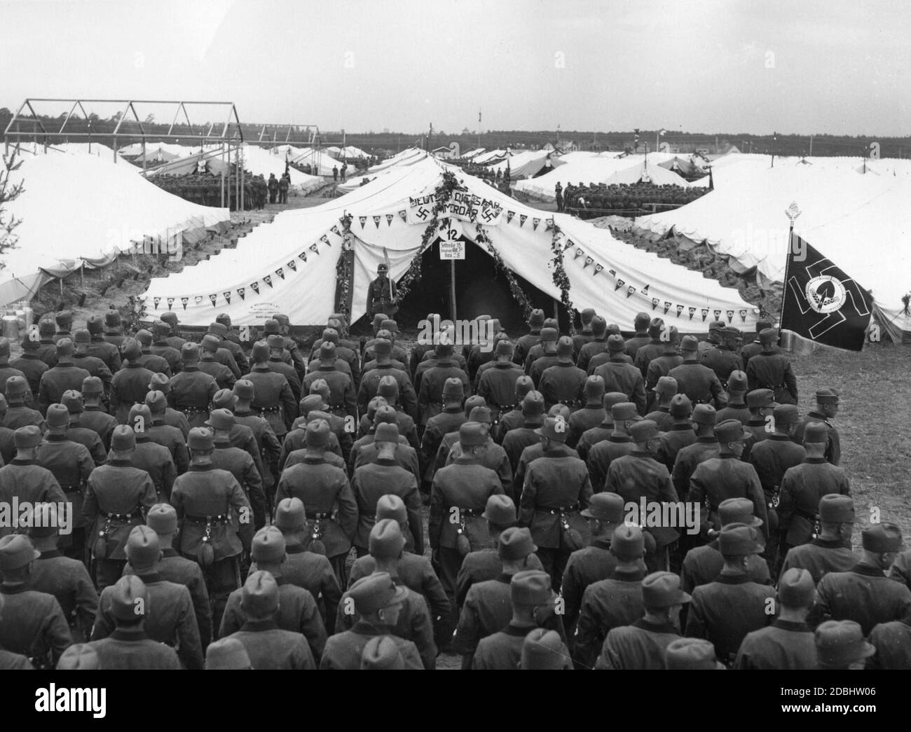 'To accommodate the various NSDAP organisations that had travelled to Nuremberg-Langwasser, a tent city was set up on the Nazi Party Rally Grounds. Here, a partial muster of the RAD with its flag on the right. On the front tent hangs a banner with the inscription ''The Saar is German forever''. Underneath is a sign with the inscription ''The 15th row of tents is occupied by Abt. 10 Bau 28''.' Stock Photo