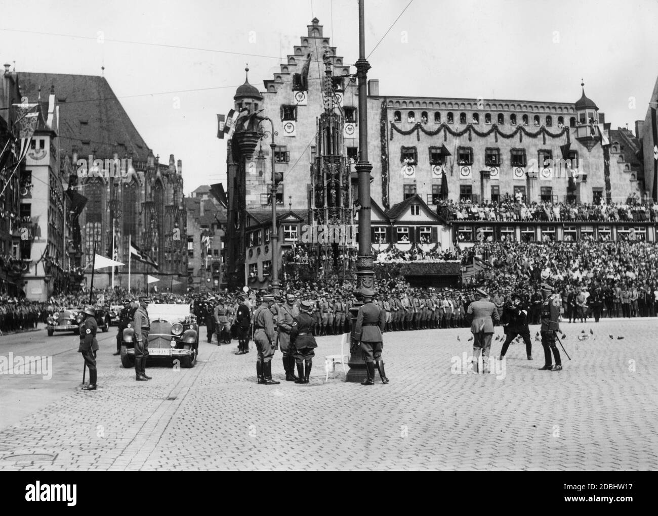 Hitler (on his left stands Viktor Lutze) greets an 80-year-old SA man on Nuremberg's main market square, the so-called Adolf-Hitler-Platz. Behind him is the Schoener Brunnen and on the right the grandstand. The scene is photographed by a photographer on the right. Stock Photo