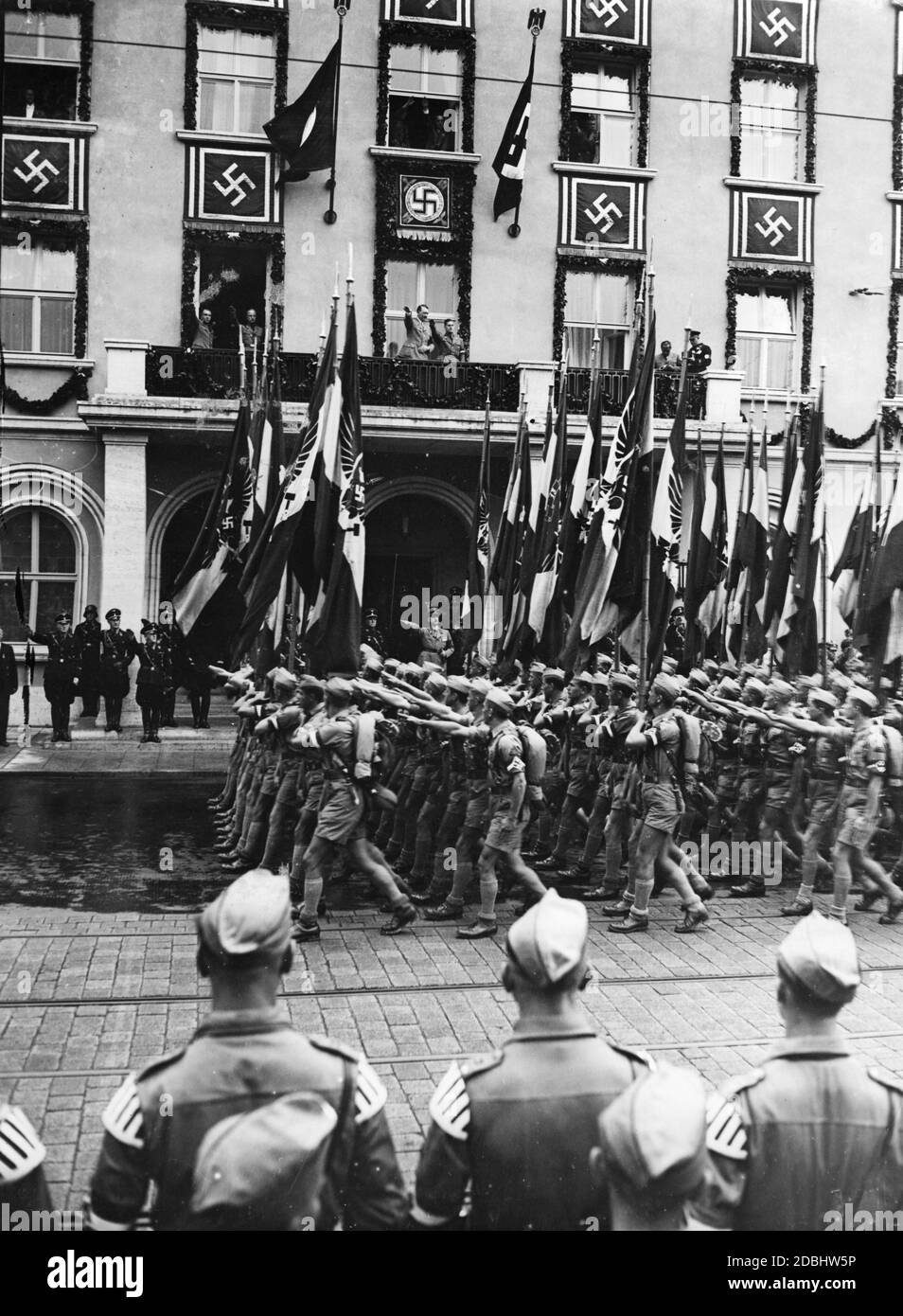 'Adolf Hitler, on the balcony of the ''Deutscher Hof'', takes the salute of the about 1,600 participants of the Adolf Hitler March of the Hitler Youth. Next to Hitler stands the Reich Youth Leader Baldur von Schirach. At the left window is Martin Bormann, at the right Heinrich Hoffmann.' Stock Photo