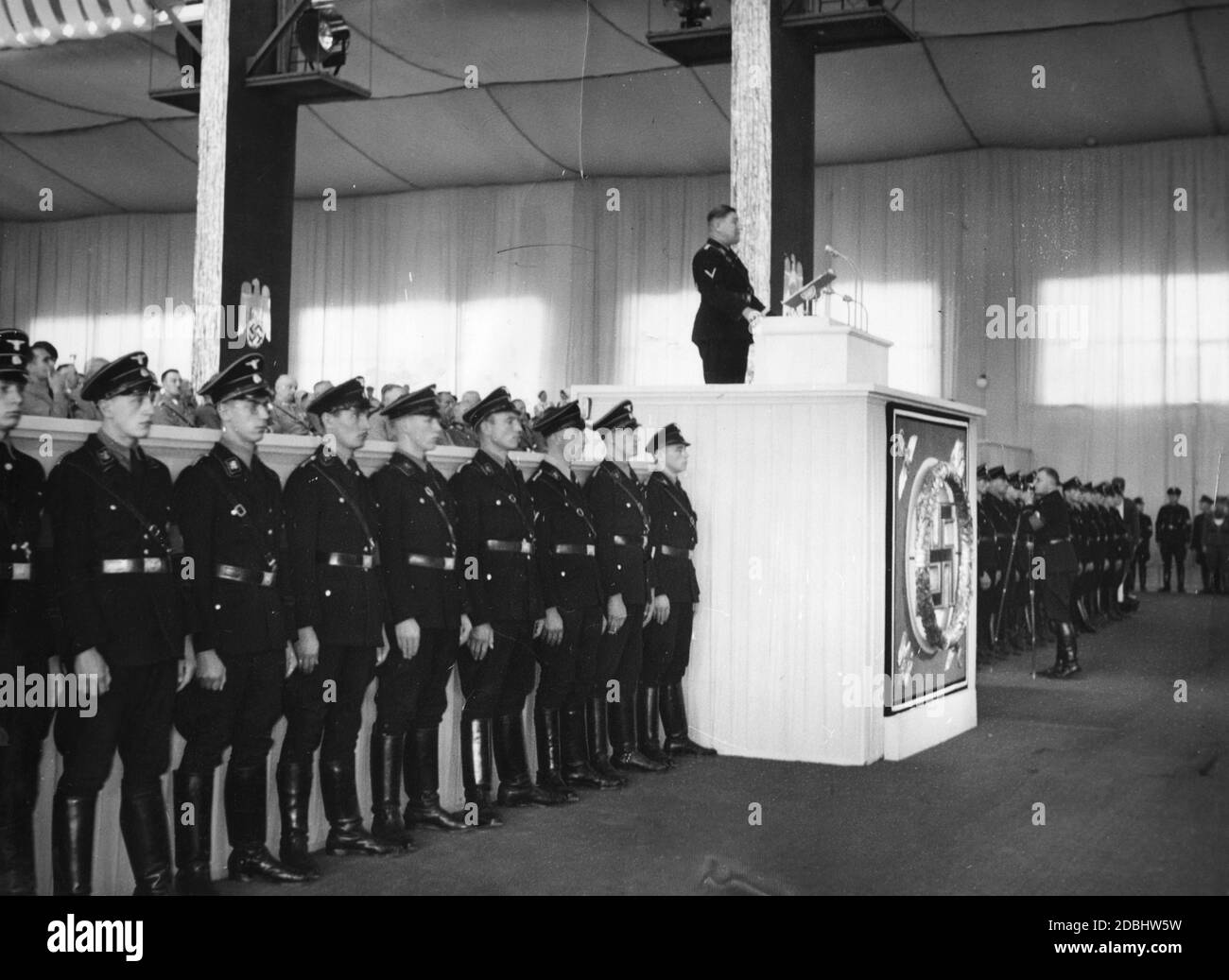 At the continuation of the NSDAP party congress in Nuremberg's Luitpoldhalle, the head of the Reichsnaehrstand (Reich Nutrition Office), Hermann Reischle is giving a speech. To the right of the speaker's podium is a photographer. Stock Photo