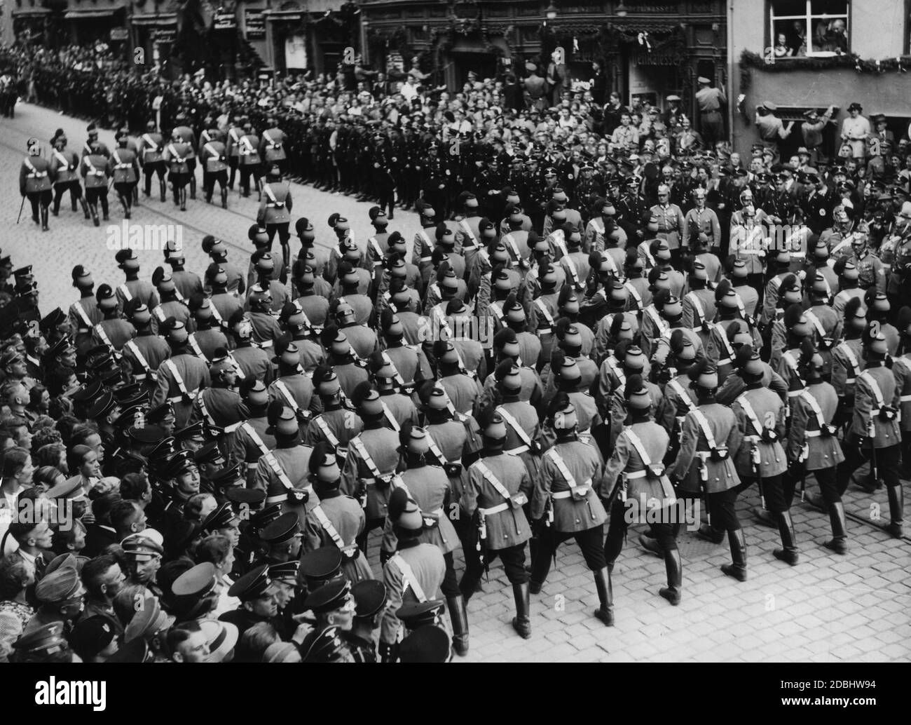 View of the parade of the police formations in their parade uniforms through the Nuremberg city centre. On the left and on the right, the cordon service of the SS. Stock Photo