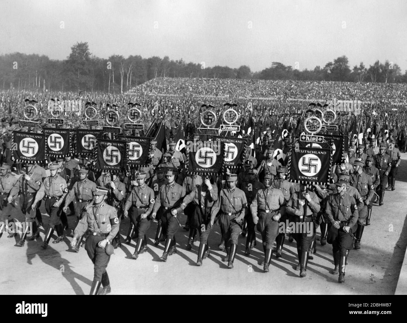 The SA troops march in step to the parade in the Luipoldarena in Nuremberg. Legible standards in the picture from left to right: Schleswig, Luebeck, Altona, Holstein, Nordfriesland, Nordmark, Itzehoe and Kiel. Stock Photo
