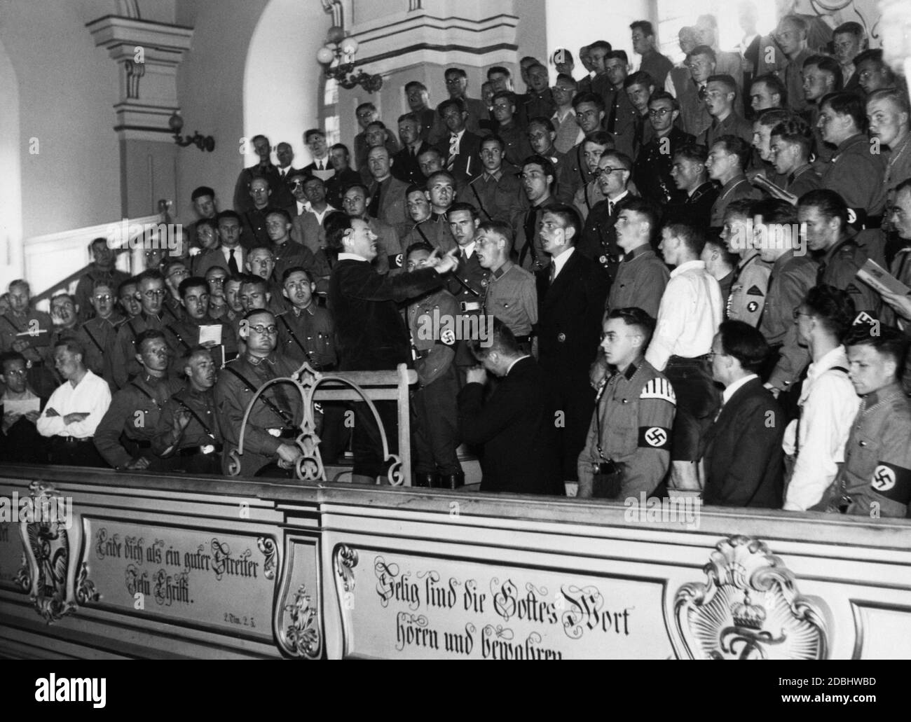 'Young SA men sing together during a military service in the Garrison Church in Potsdam. The conductor of the choir is Dr. Hensel Janiczek. This mass is celebrated in the first Reichssingwoche (''Reich Singing Week''). The event is organized by the National Socialist organization ''Kraft durch Freude'' (''Strength through Joy'') and the ''Deutsche Studentenschaft'' (''German Student Union''). The choir is made up of students and members of the German Labor Front.' Stock Photo