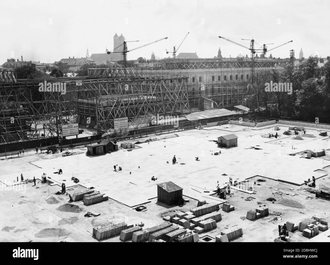 In the foreground the laying of stone slabs on the Koenigsplatz. On the left, the construction of the Ehrentempel (Temple of Honour) for the National Socialists killed in the Beer Hall Putsch. And in the back right, the construction of the administration building of the NSDAP. At the back in the middle, the Frauenkirche. Stock Photo