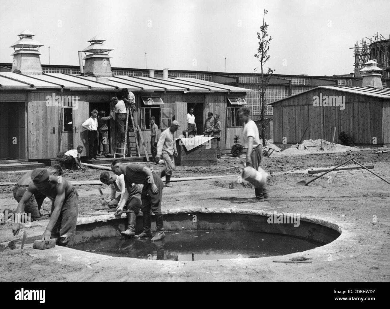 In the course of the Deutschlandausstellung (Germany exhibition) at Kaiserdamm in Berlin, members of the Labour Service are building a paddling pool. In the background are the barracks of the Labour Service. Stock Photo