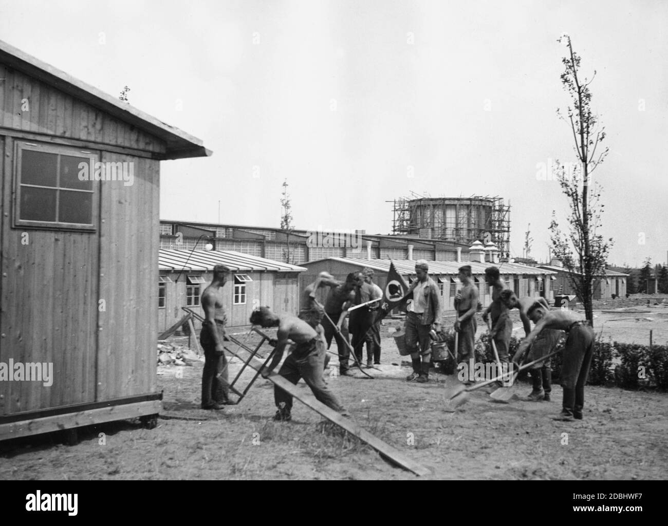 Members of the Labour Service are involved in the construction work for the Deutschlandausstellung (Germany exhibition) at Kaiserdamm in Berlin. In the background, the barracks of the Labour Service. Stock Photo