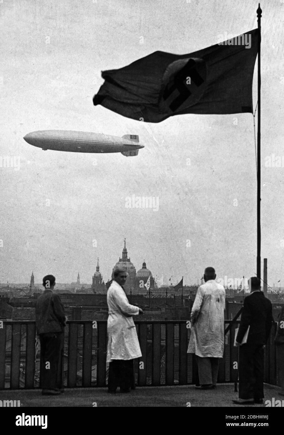 'The airship LZ 129 ''Hindenburg'' in the picture with a swastika flag over Berlin during an Olympic flight. In the background is an Olympic flag and the Berlin Cathedral.' Stock Photo