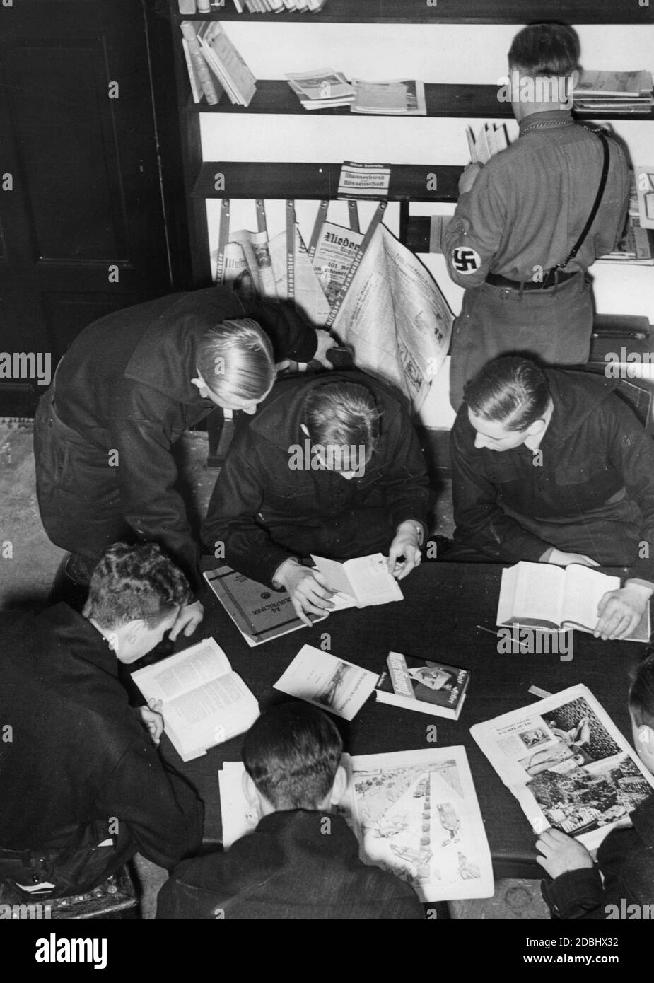 'Students of the university group of the NSDStB in the reading room of their new comradeship house, the ''Melanchthonhaus'' in Sebastianstrasse, Berlin, with a bookcase and newspaper corner. On the table is a copy of Adolf Hitler's ''Mein Kampf''' Stock Photo