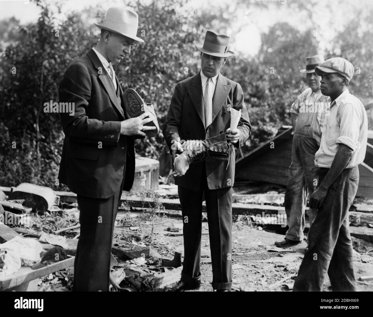 Louis Bormann, New Jersey police officer, and Martin Tobin, New York police officer, with a pair of shoes found in the home of Bruno Hauptmann in Bronx, New York, the prime suspect in the Lindbergh child abduction case (undated photo). Stock Photo