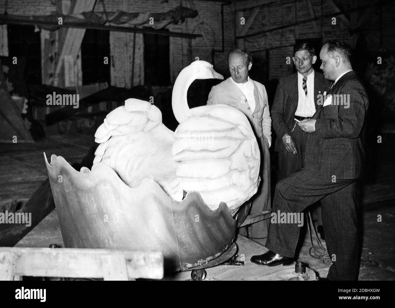 The scenic Prof. Emil Preetorius, the technical director Paul Eberhardt and Kurt Palm, costume designer, (from left to right) examine the finished swan for the staging of Lohengrin. Stock Photo