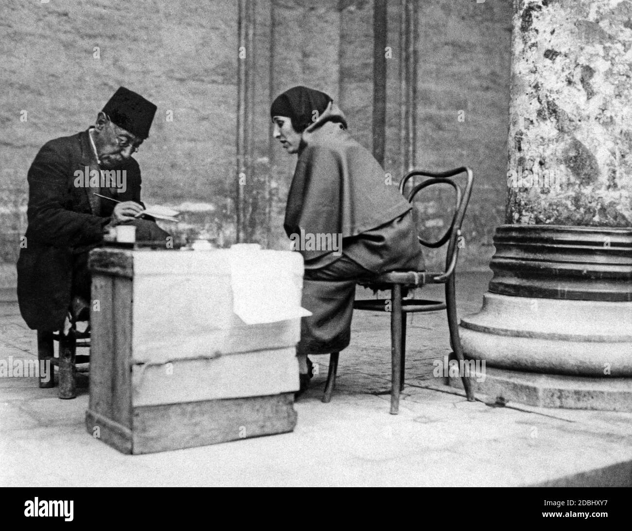 A young illiterate Turkish woman dictates a letter to a letter writer outside a mosque. Illiteracy was a big problem in Turkey until Kemal Atatuerk introduced the Latin alphabet. In particular, the low level of education of women leads to high illiteracy. Stock Photo