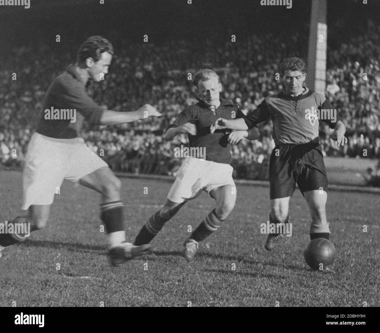 The Bavarian player Georg Frank (right) plays around the two Berlin defenders Heinz Emmerich (center) and Hans Bruhnke (left). Bavaria wins the game with 6:1 and thus the Hitler Cup. The Adolf Hitler Cup 1933 was the first Gauauswahlwettbewerb to be held and served as the successor to the Federal Cup. Since the final ended with a 2:2 score, this replay was convened at the Grunewald Stadium in Berlin. Stock Photo