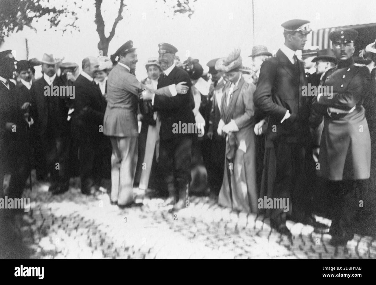 Grand Duke Ernest Louis of Hesse-Darmstadt (centre left) and Prince Henry of Prussia (centre right) embrace and greet each other. They are standing on the Hanauer Landstrasse in Frankfurt am Main at the finish of the third Herkomer competition, which ended there on June 13, 1907. Stock Photo