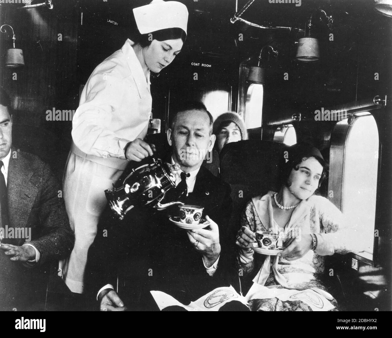Stewardesses in the early days of aviation wore white nurse-like uniforms. This stewardess is serving coffee to passengers on a trimotor Boeing 80A flying the Chicago-San Francisco route of Boeing Air Transport, 1930. (Photo by Federal Aviation Administration/RBM Vintage Images) Stock Photo