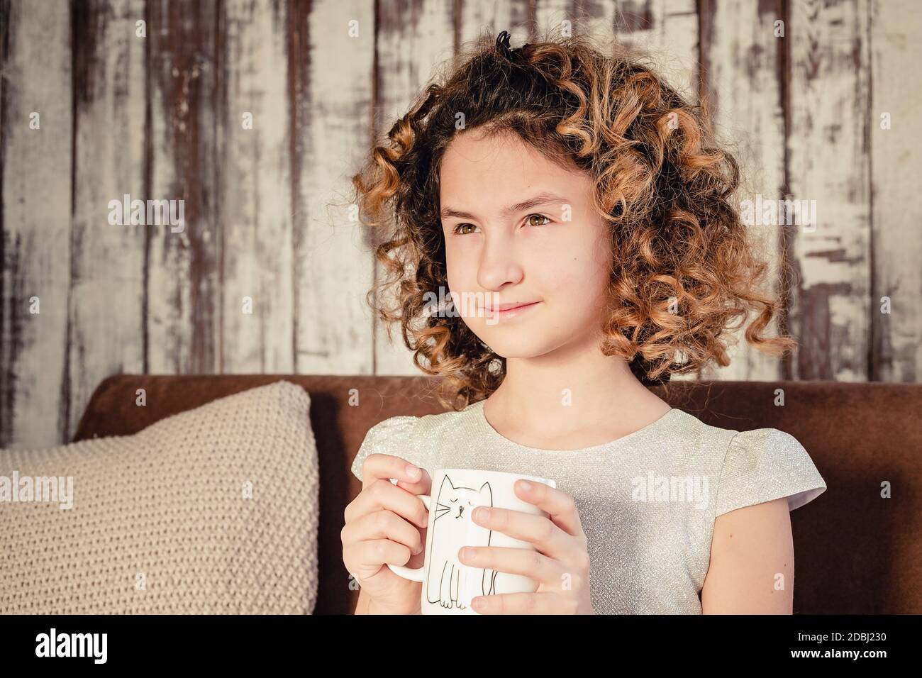 Cute caucasian girl in a beautiful dress is holding a mug with a hot drink. Copy space. Stock Photo