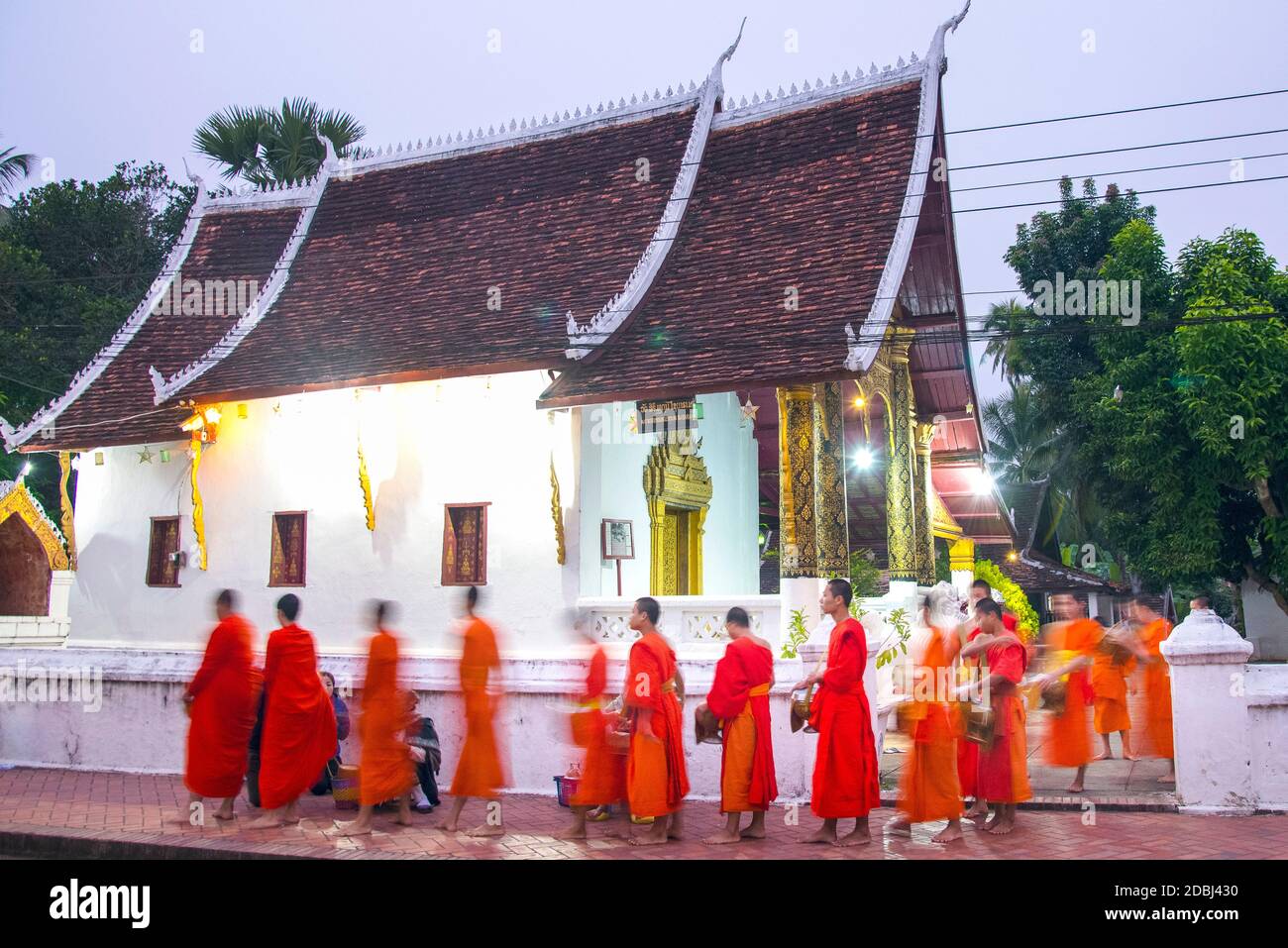 Buddhist monks receive rice from locals during an early morning daily ritual known as Sai Bat (morning alms) in Luang Prabang, Laos Stock Photo