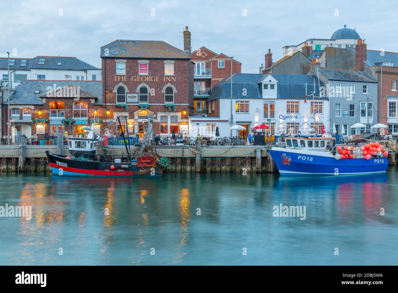 View of boats in the Old Harbour and quayside houses at dusk, Weymouth