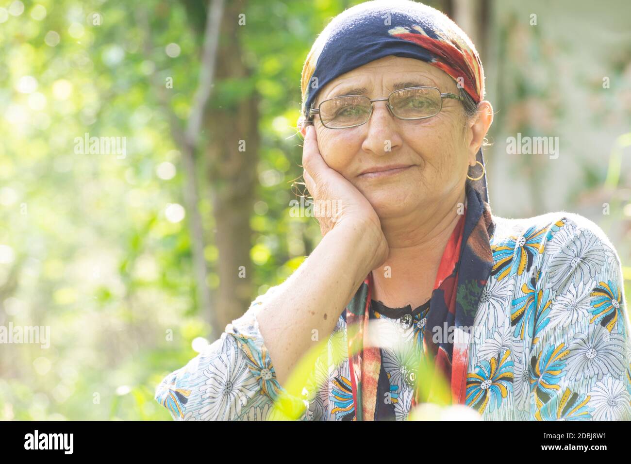 Close up portrait of a senior 68 years old woman with eyeglass and scarf at spring time outdoor area Stock Photo