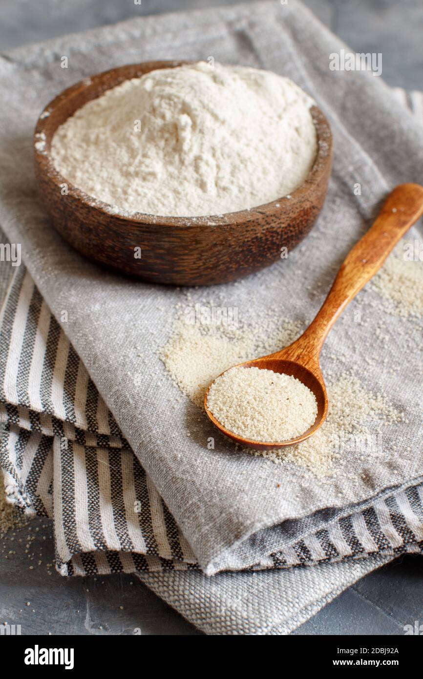 A bowl of Raw fonio flour and seeds  in a spoon on a napkin close up. Alternative flour Stock Photo