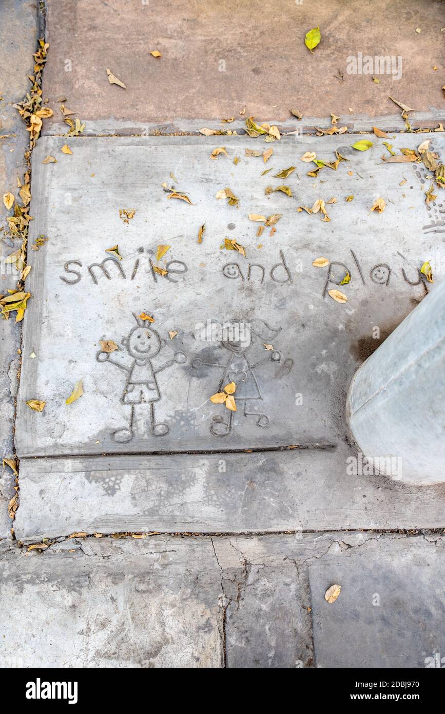 Top View of children drawing with a Smile and Play message written in the cemented pavement on a sidewalk in Lima, Peru. Stock Photo