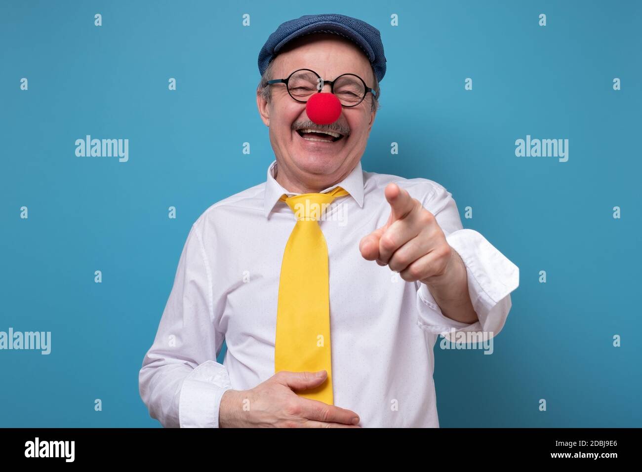 Senior cheerful man with red nose laughing pointing at you. Stock Photo