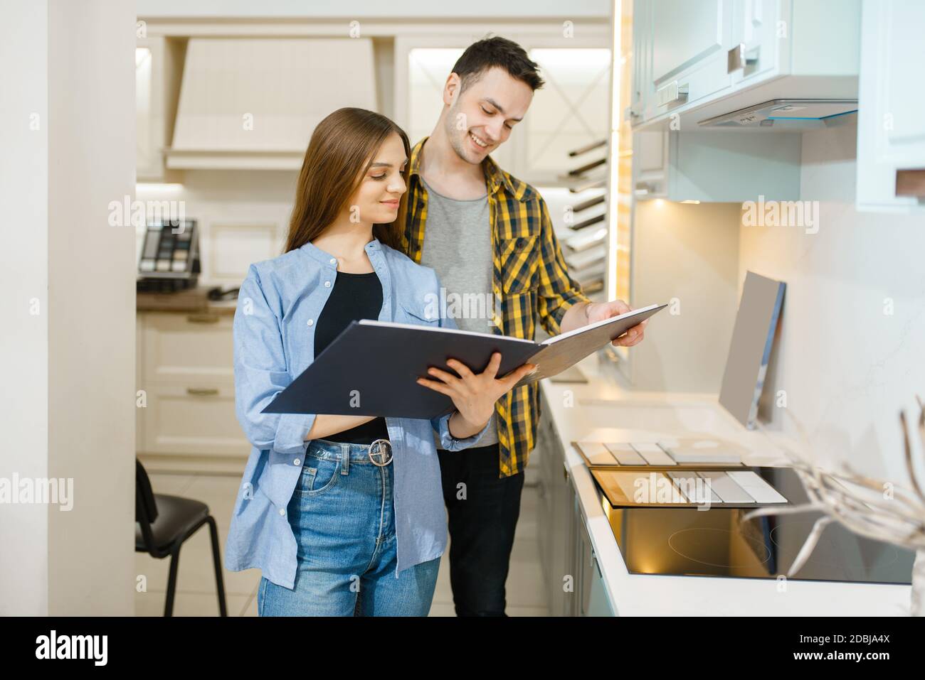 Family couple choosing kitchen garniture in furniture store showroom. Man and woman looking assortment in shop, husband and wife buys goods for modern Stock Photo