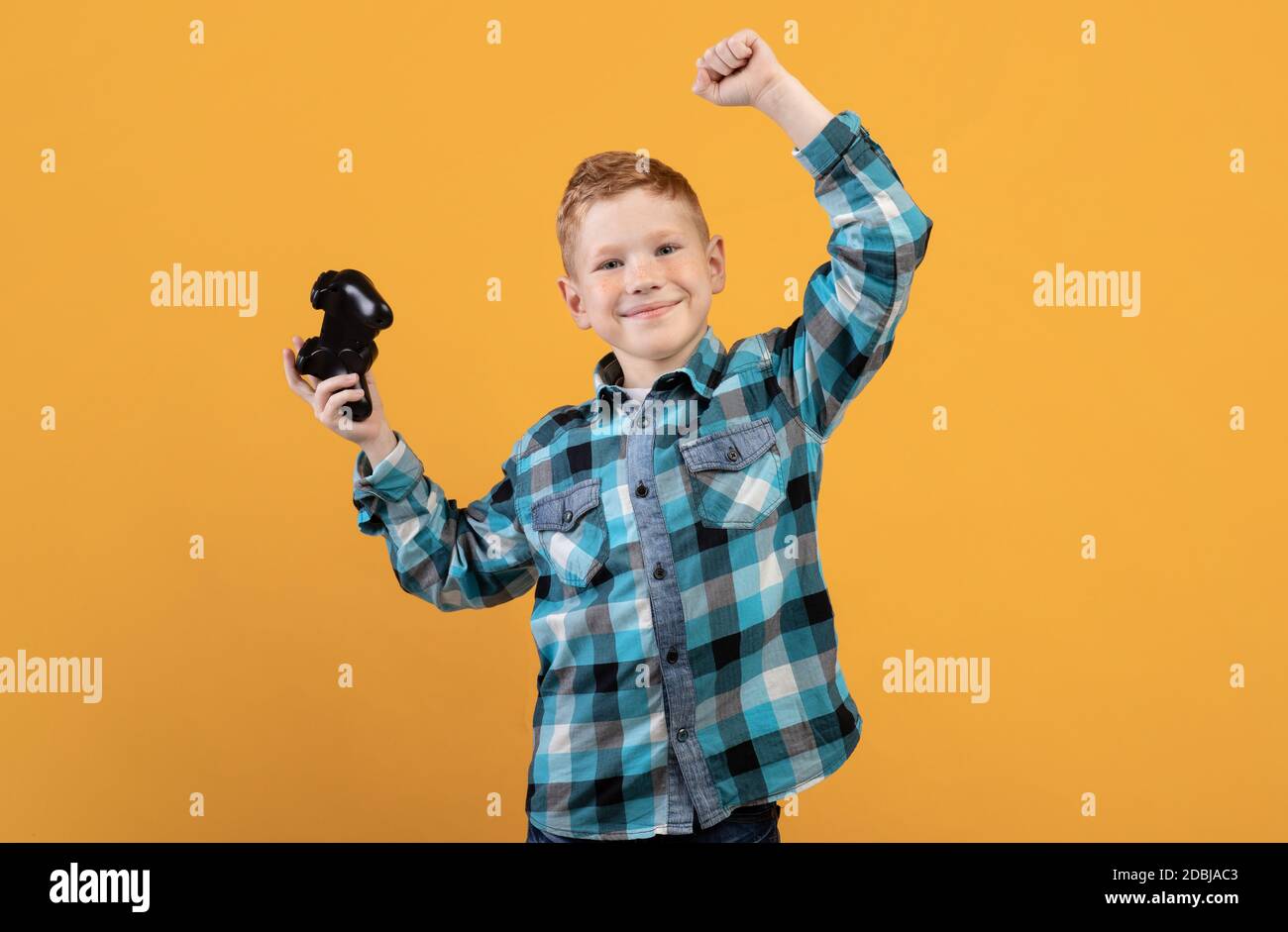 Happy boy playing video game with joystick, celebrating success Stock Photo