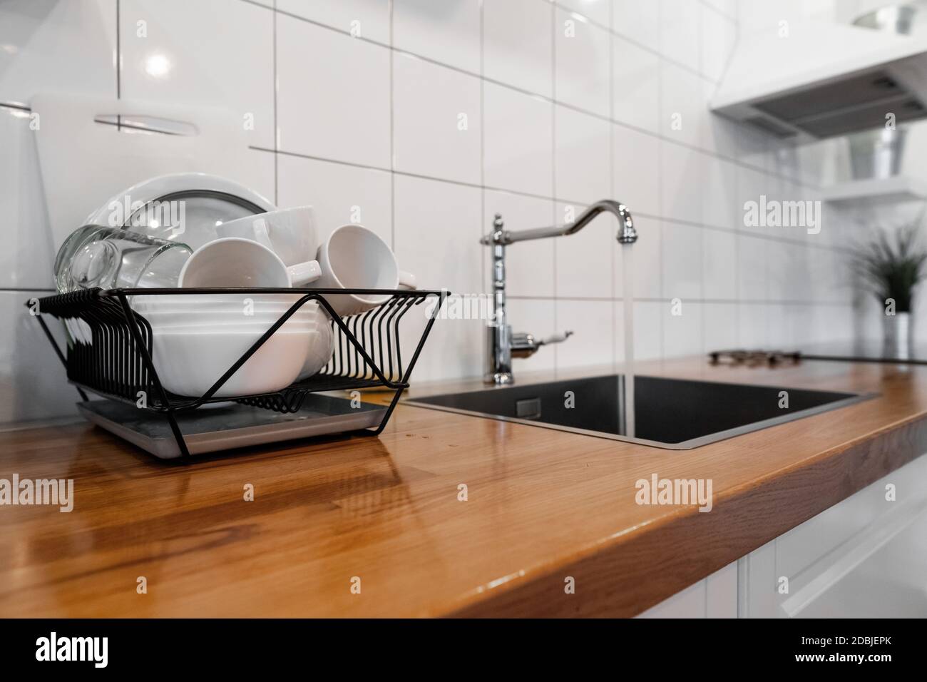 Budget and lightweight antimicrobial dish drainer with drain board at  modern scandinavian kitchen. Dish rack holds many dishes and cups against  wooden Stock Photo - Alamy