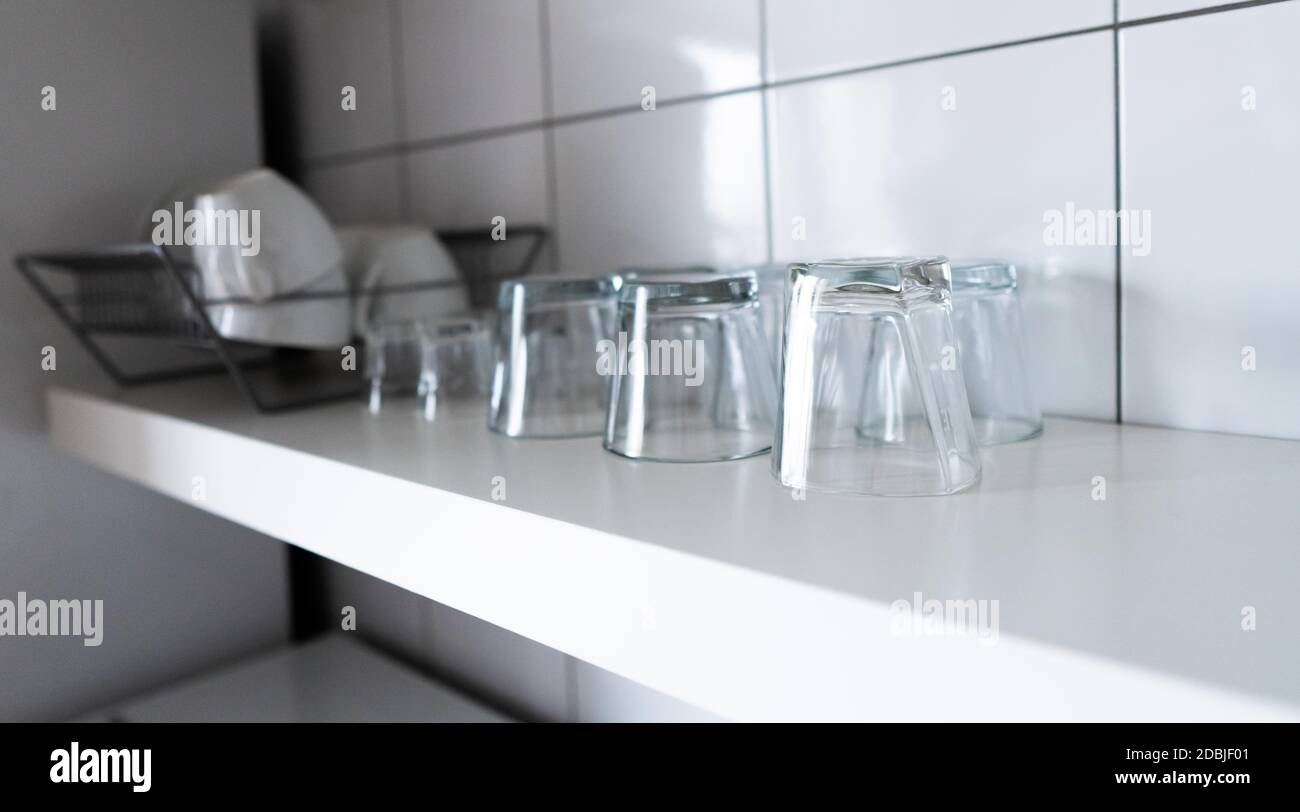 https://c8.alamy.com/comp/2DBJF01/white-wooden-shelf-and-budget-lightweight-dish-rack-with-dishes-cups-and-glasses-against-wall-tiles-at-modern-scandinavian-kitchen-wide-kitchen-shel-2DBJF01.jpg