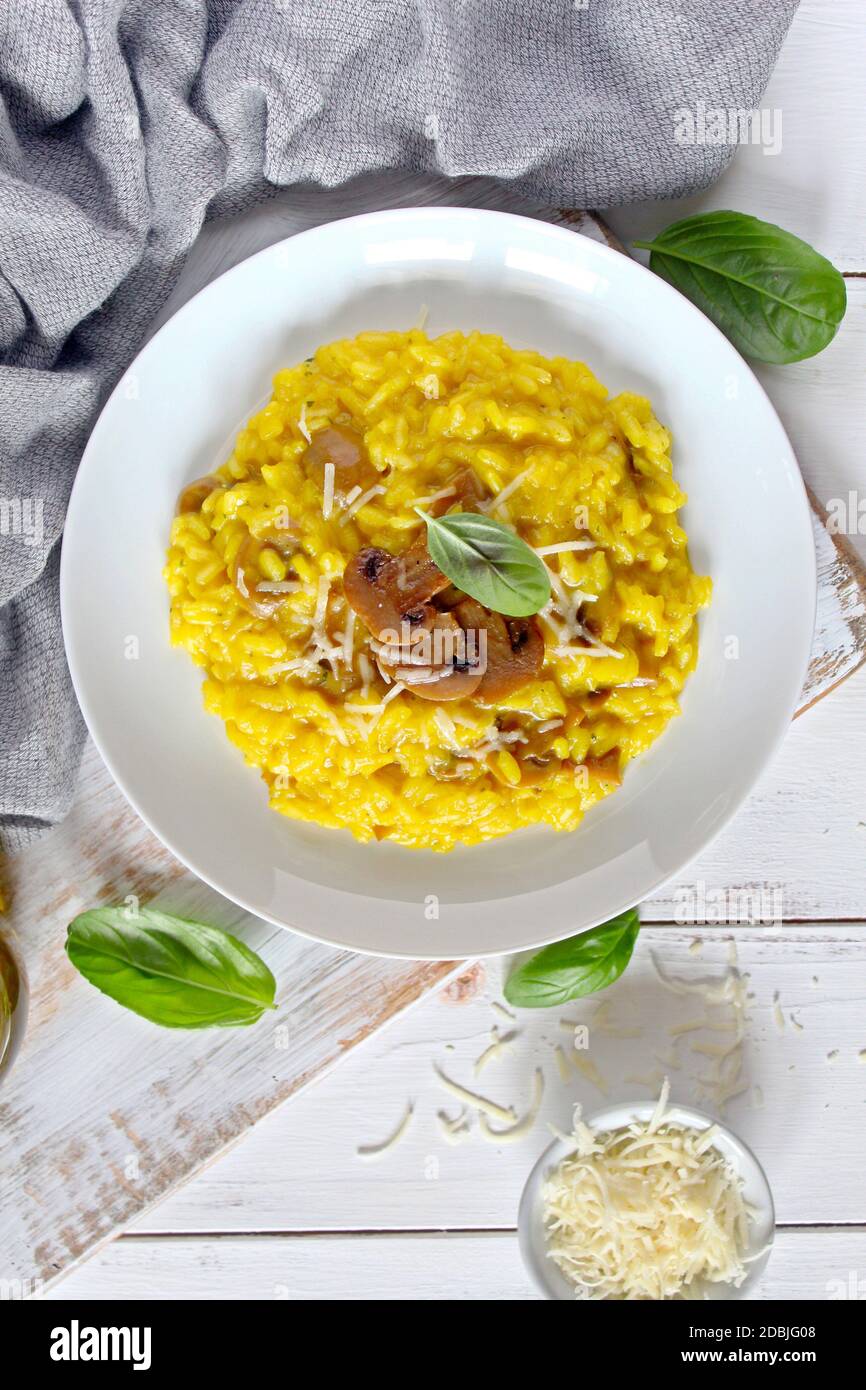Traditional Italian risotto with mushrooms, saffron and parmesan cheese on wooden background. Top view. Stock Photo