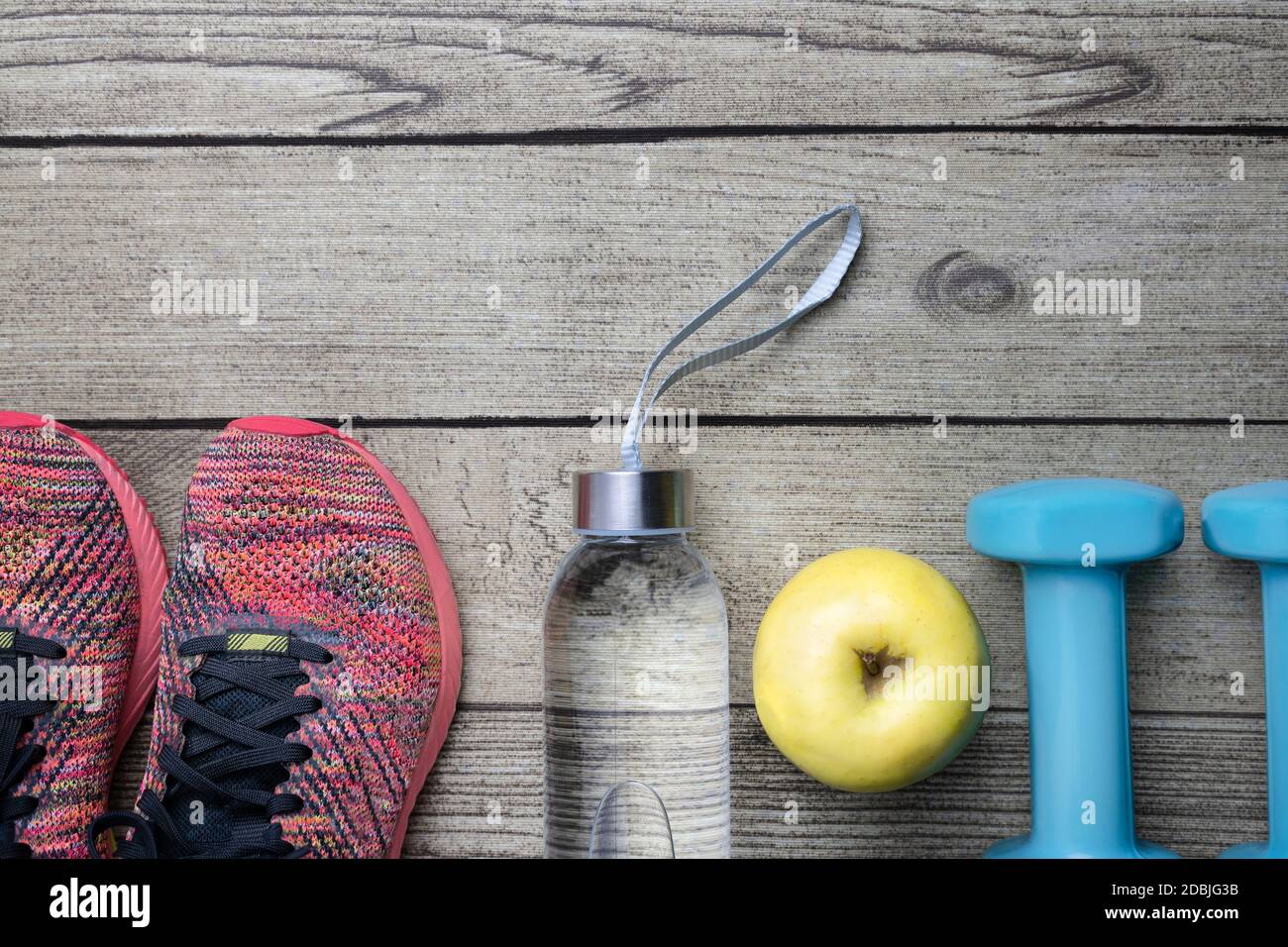 Fitness equipment top view on wooden background.Sneakers, dumbbells , apple and water bottle.Healthy lifestyle , home workout concept.Copy space for t Stock Photo