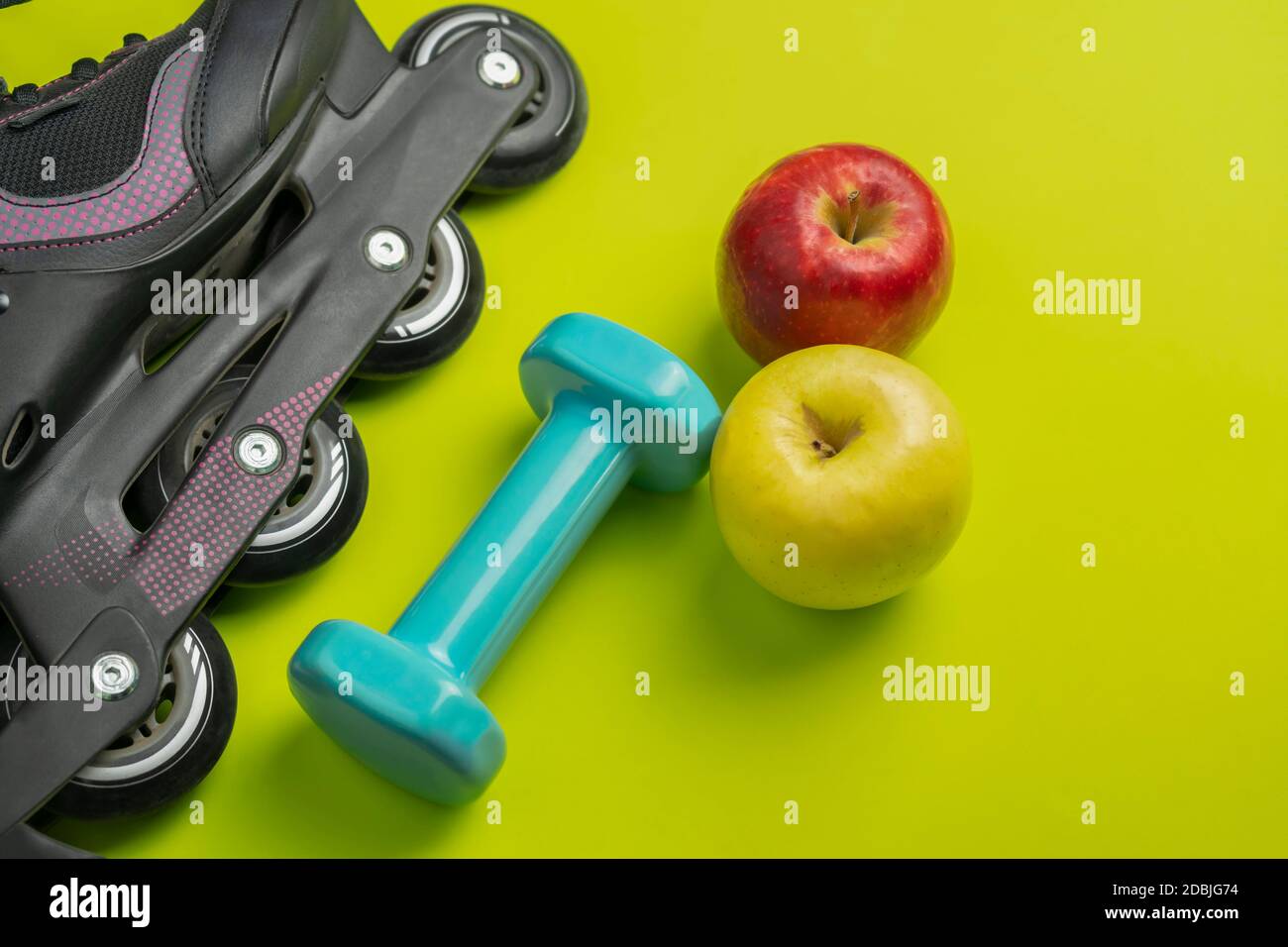 Sport fitness equipment flat lay with healthy food .Two apples ,dumbbell,roller skate, and headphones on green background .Top view healthy lifestyle Stock Photo