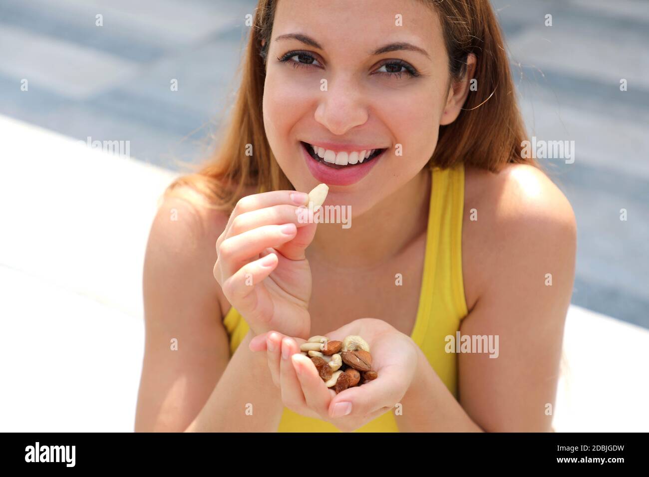 Close up fitness girl eating healthy mix of nuts seeds dried fruit