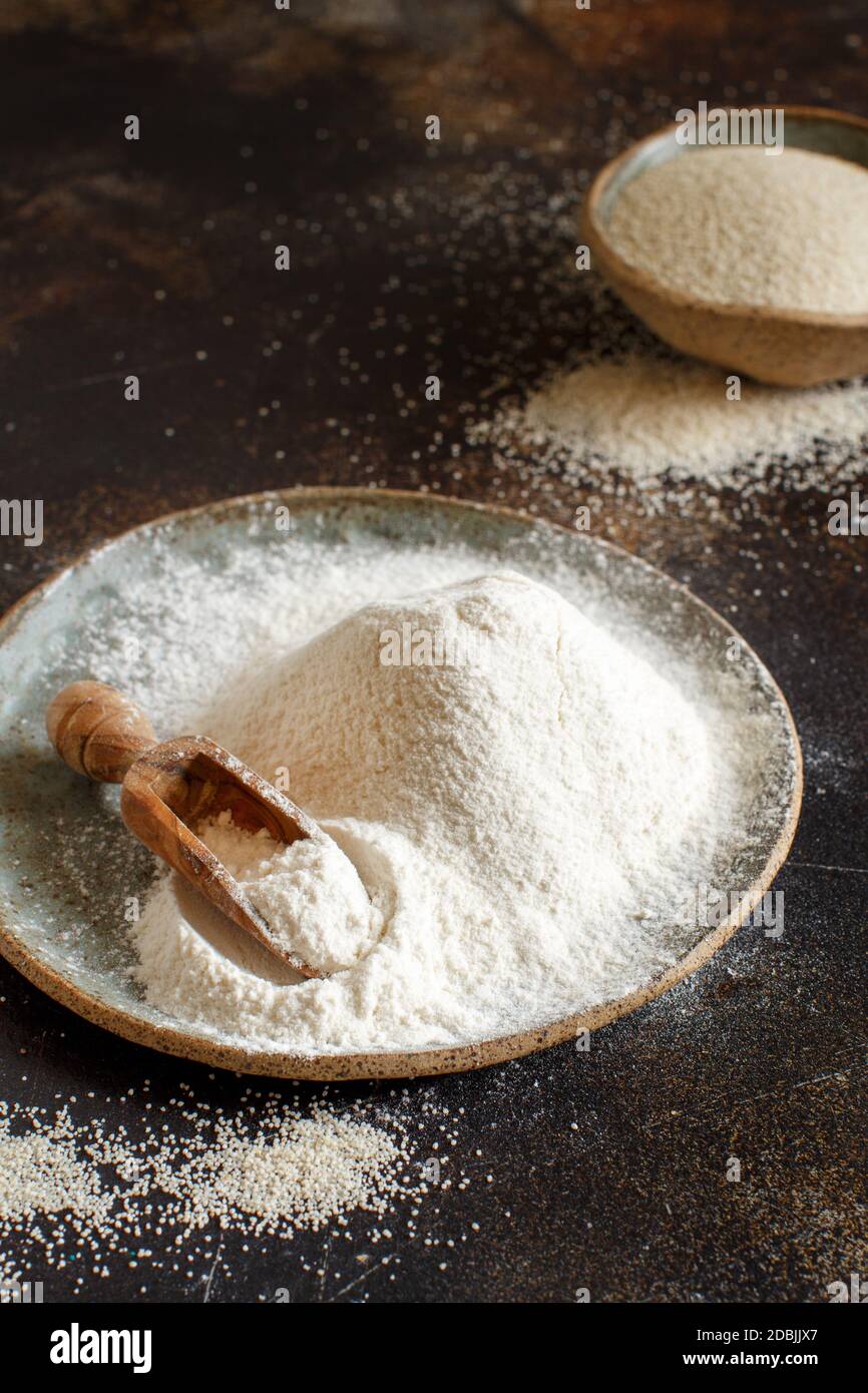 Raw fonio flour and seeds with a spoon on dark background close up. Alternative flour Stock Photo
