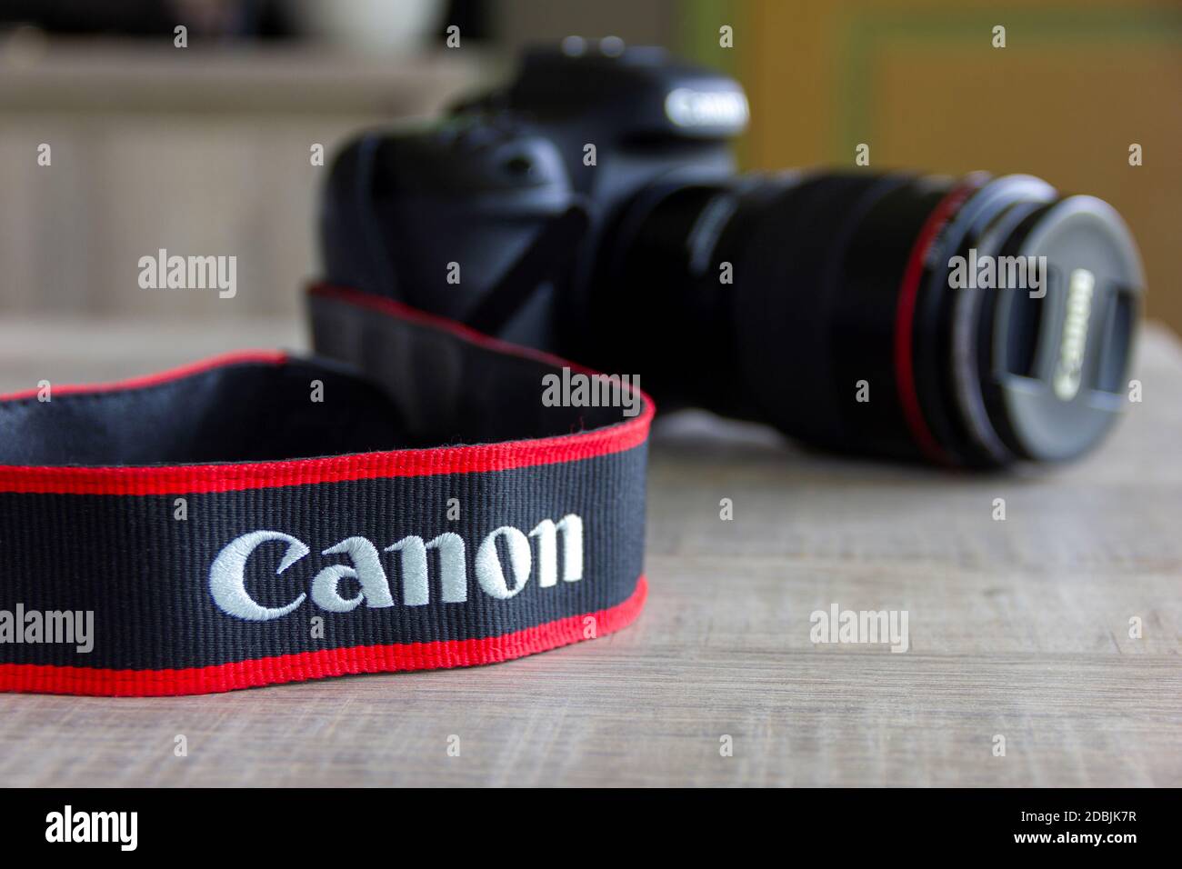 Brecht, Belgium - April 30 2020: A portrait of a canon camera lying on a table with the strap with the company logo in focus. Stock Photo