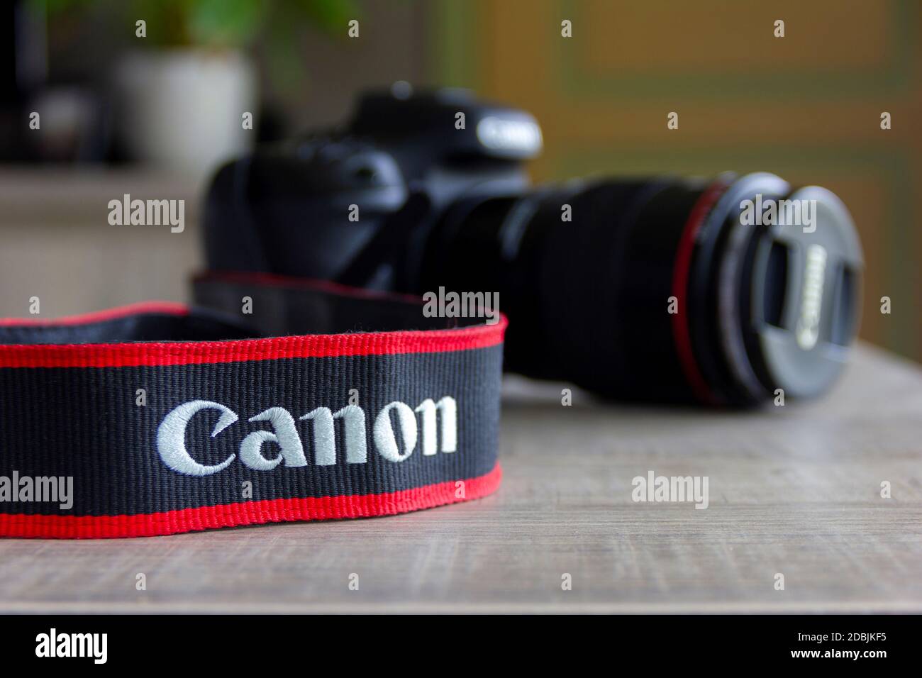 Brecht, Belgium - April 30 2020: A portrait of a blurred canon 7D mark II camera lying on a table with the strap containing the company logo in focus. Stock Photo